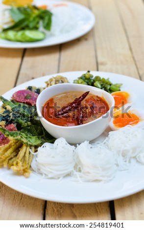 Rice Noodles in sweet curry sauce/ Traditional Thai cuisine, rice vermicelli   served with boiled egg  , sweet peanut  sauce and vegetable  on wood table.Selective Focus.