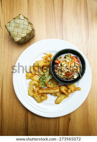 Thai style appetizer of fried tempura vegetable  with dipping sauce.Som Tam Thai - Thai Green Papaya Salad with peanuts. Papaya salad set on wood table.