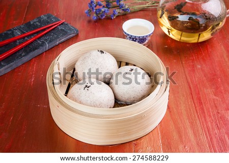 steamed pork buns, chinese dim sum with hot tea in tea pot set on red table background