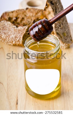 Honey in a jar, slice of bread and honey dipper on an old vintage planked wood table from above. Rural or rustic style breakfast concept. Background layout with free text space.