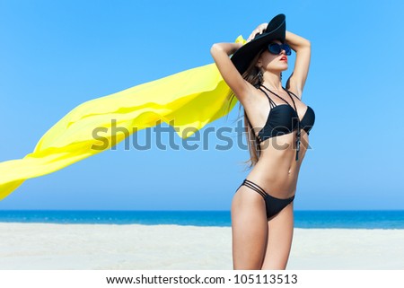 Beautiful woman standing on the beach with bright fabric