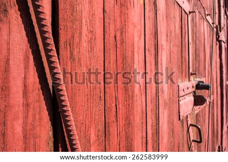 A red painted garage door with reinforcing metal rod and padlock