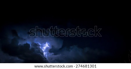 Electric Lightning bolt inside a thunderhead of dark blue clouds at night