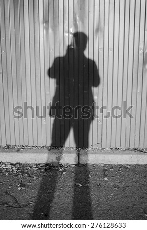 Photographer taking a photo casting shadows on a wall in black and white