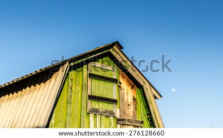 Late evening Moon rises above a green painted rustic shed