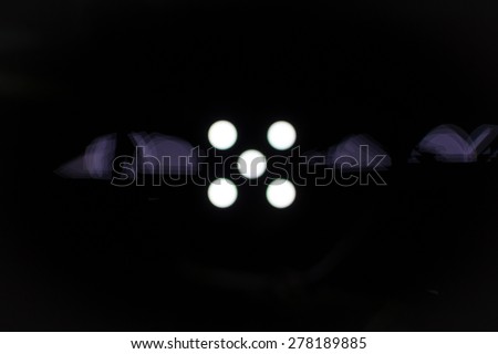 Five white dots on a black background with light defraction in a horizontal position