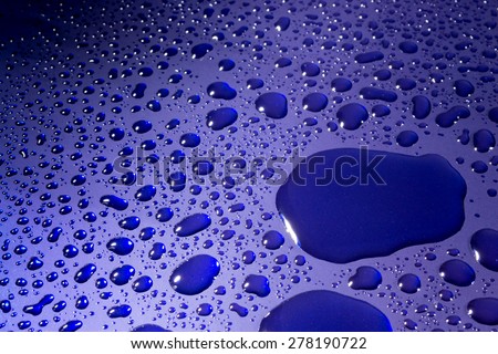 Clear water droplets reflected from bright blue paint