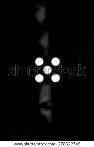 Five white dots on a black background with light defraction