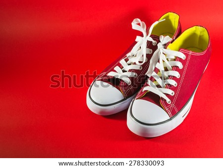 Pair of new red canvas trainers on a dark-red background