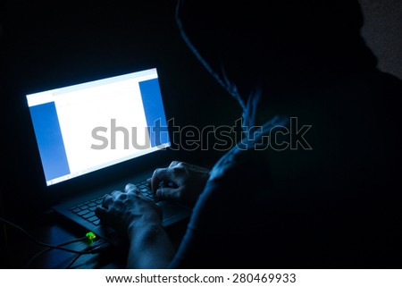 Single solitary computer hacker works in the dark committing crime