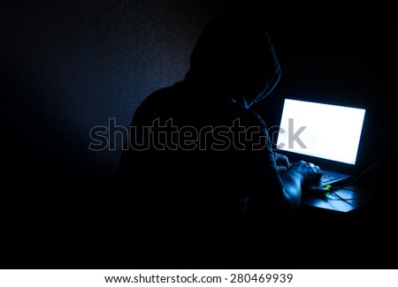Single solitary computer hacker works in the dark committing crime
