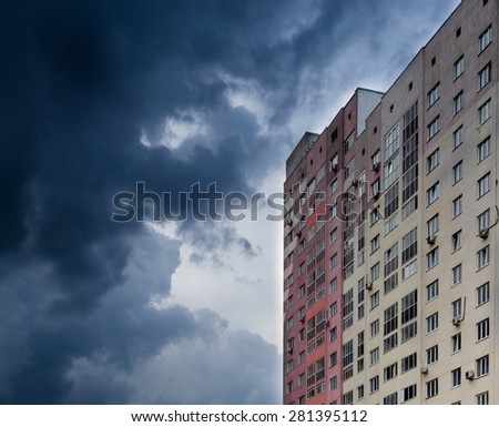 Single High-rise apartment block facing a dark grey storm cloud