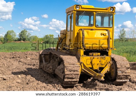 Single earth moving digger covered in mud with cloudy sky