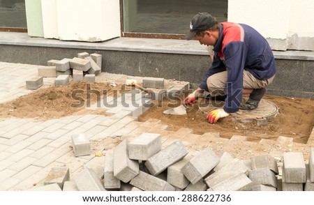 UFA/BASHKORTOSTAN - RUSSIA 13th June 2015 - Uniformed builder lays sand foundation for stone brick block paving in Ufa Russia in July 2015