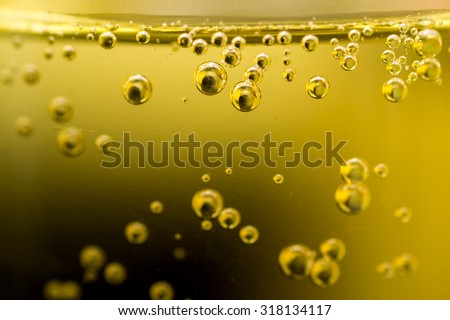 Closeup Macro of many fizzy bubbles in a glass of golden colored liquid