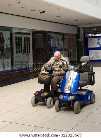 CHELMSFORD - ENGLAND 1ST SEPTEMBER 2015 - Elderly pensioner waits sitting on his mobility scooter in a Chelmsford Shopping centre during the summer of 2015 in England