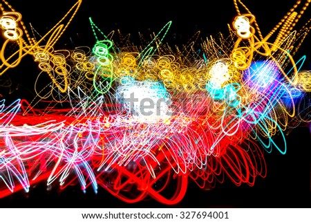 Neon lights form an abstract light painting image as they merge and collide against a black void like background, Multicolored light streaks of red, yellow, white, and pink