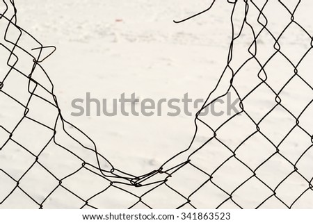 Broken chain link fencing with a white winter snow background