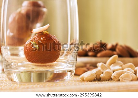An Indian dessert Gulab Jamun dipped in sugar syrup and topped with Cashews,almonds and pistachio