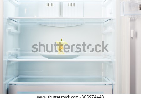 Apple core on white plate in open empty refrigerator. Weight loss diet concept.