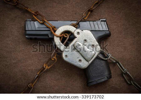 Gun Control Concept - Pistol behind Lock and Chain