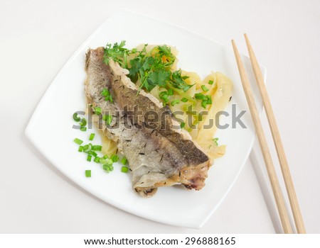 Fried fish with vegetables on square plate with chopsticks