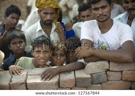 LAHORE, PAKISTAN- AUG 2: Unidentified people and children in brick kiln are waiting for the food from relief team on August 2, 2012 in Lahore, Pakistan. Malnutrition is a common problem in Pakistan.