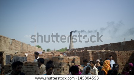 LAHORE, PAKISTAN- AUG 1 2012: Unidentified people work at a brick kiln on August 1 2012 in Lahore, Pakistan. People are exploited in the brick kiln and they suffer from poor health.
