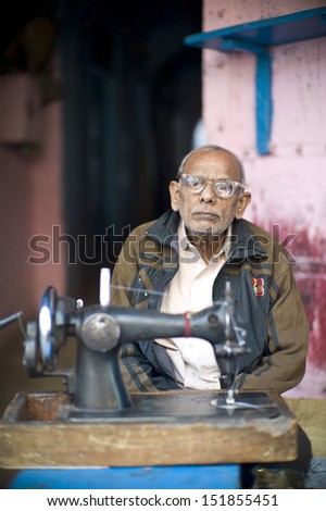 DELHI, INDIA - NOV 18: Unidentified old man is sewing in a classical street in Old Delhi. November 18, 2012 in Delhi, India. The lifestyle in old delhi is still well kept like that in 100 years ago.