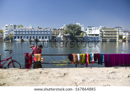 UDAIPUR, INDIA - JAN 30: Indian lady is doing the laundry by the lake in Udaipur, India on January 30 2013. The lake is also the source of water for the city.