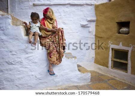 JAISALMER, INDIA - JAN 12: Unidentified Indian woman and her child live in Jaisalmer Fort in Thar desert on January 12, 2013 in Jaisalmer, India. Jaisalmer Fort is the only livable fort in India.