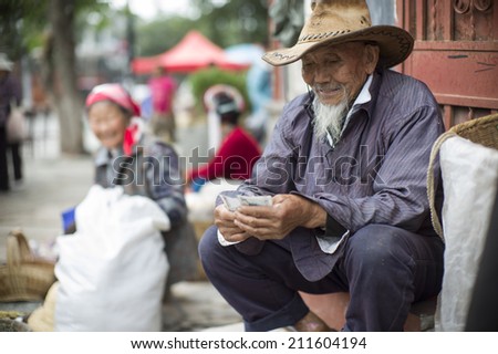 DALI, CHINA - MAY 15: An old man is selling tea in the flea market on the street in Dali, China on May 15 2014. He is from a minority ethnic, called Bai.