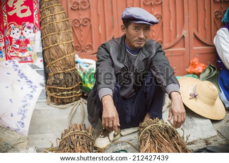 DALI, CHINA - MAY 15: An old man is selling tea in the flea market on the street in Dali, China on May 15 2014. He is from an ethnic minority called Bai.