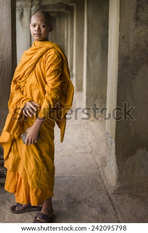 SIEM REAP, CAMBODIA - NOV 16: Buddhist monk in yellow robes visiting one of the famous temples of Angkor Wat, Siem Reap, Cambodia on November 16 2014.