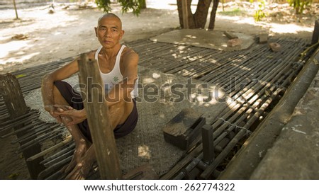 BAGAN, MYANMAR - MAR 2: An old man rests on a bamboo bed under the tree outside the temple Gawdaw Palin on March 2 2015 in Bagan, Myanmar.