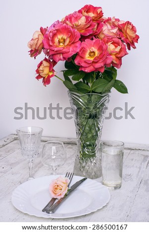 table setting with roses bouquet on vintage white background