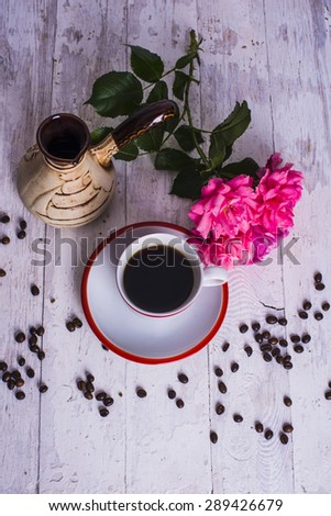 coffee cup, coffee beans and roses on wooden background