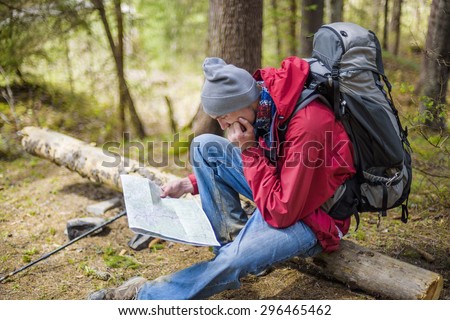 young caucasian male with a map in the forest, hiker looking at map outdoors