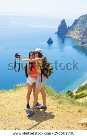 two young caucasian females making self portrait on a cliff above the sea