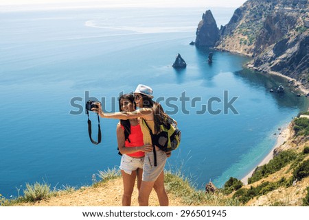 two young caucasian females making self portrait on a cliff above the sea