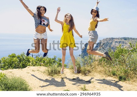 three young cheering  friends jumping on a cliff above the sea