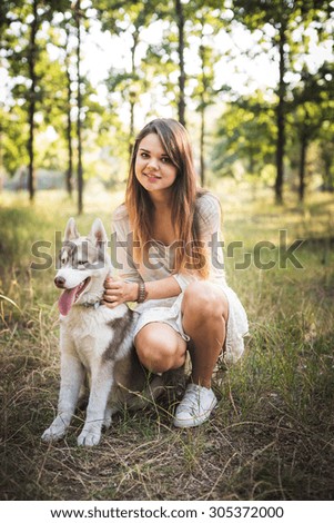 young caucasian female with siberian husky puppy in park