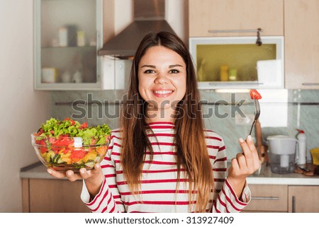 young caucasian female eating salad on kitchen. Healthy organic food, healthy living concept
