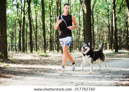work out with dog. Young caucasian male running with siberian husky dog. Man and husky jogging in park