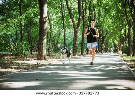 work out with dog. Young caucasian male running with siberian husky dog. Man and husky jogging in park