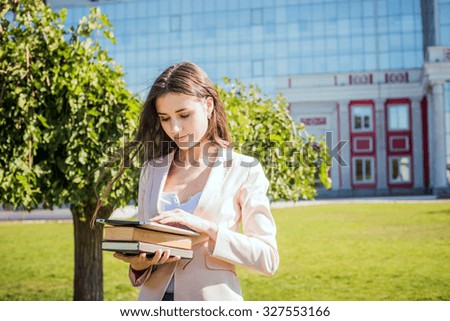 young caucasian female student with books and tablet on campus, student study in campus area