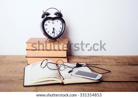 books, alarm clock, notepad, cellphone with earphones  on wooden background. Education equipment, education concept