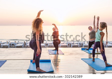 yoga class - group of people practicing yoga during sunrise