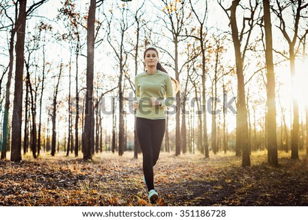 female running in park. Young woman jogging in autumn forest