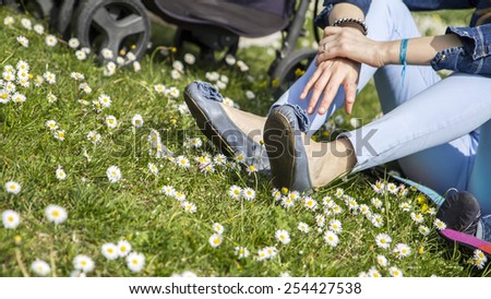 Young girl enjoying a sunny day outdoor on a green meadow; vivid colors, fashionable clothes.